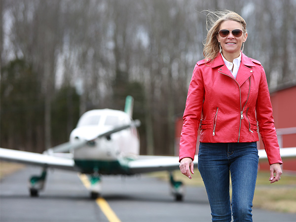 Cool Girl and pilot Natalie Kelley walking in front of a small airplane.